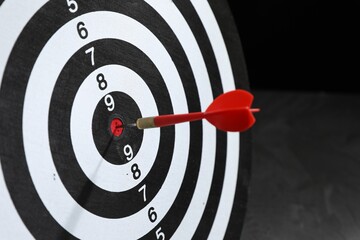 Targeting. Dart board with arrow on dark background, closeup
