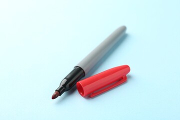 One red marker on light blue background, closeup. Space for text