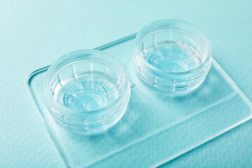 Contact lenses in case on light turquoise background, closeup