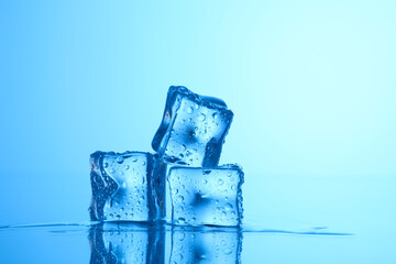 Cubes of clear ice on light blue background, closeup. Space for text © New Africa