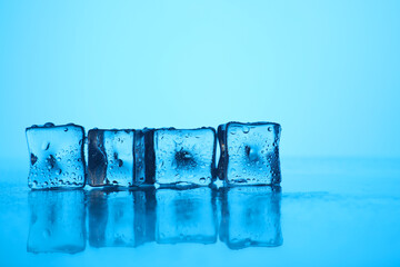 Cubes of clear ice on light blue background, closeup. Space for text
