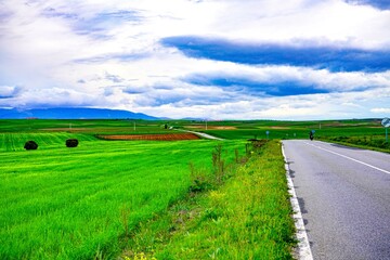 Carretera de asfalto entre campos verdes y una motocicleta.