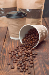 Coffee beans spill out of paper cup. close-up of coffee beans. Concept of aromatic fresh coffee. Coffee shop, Morning. Break. Coffee background.