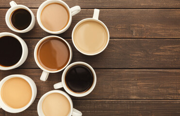 Border of various kinds of coffee in cups of different size on rustic wooden table, top view, copy space