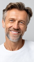 Obraz premium Close-up portrait of a mature man with a graying beard and blue eyes smiling against a solid backdrop.