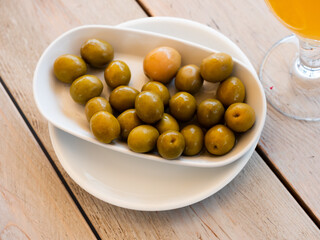 Closeup of plate of pickled green olives with a stone, spanish appetizer