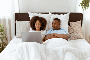 Shopping online, chat and ignoring husband. Sad offended young african american male with crossed...