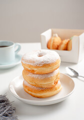 Stack of powdered sugar donuts on napkin with coffee in background. Perfect for bakery, breakfast, dessert, or cafe-themed food content recipes, articles or any cooking content