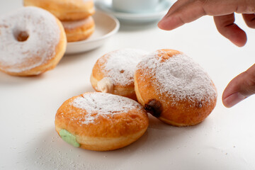 Powdered jelly-filled donuts with creamy fillings on white background – sweet pastry dessert perfect for bakery, breakfast, recipes, articles, snack-theme or any cooking content.