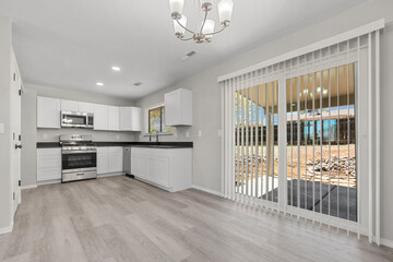 An empty kitchen with a sliding glass door and a stylish chandelier