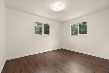 An empty room featuring hardwood floors and two spacious windows