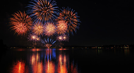 Colorful fireworks illuminating a night sky over a lake  