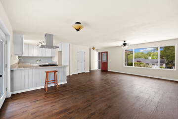A vacant living room featuring beautiful hardwood floors and a kitchen nearby
