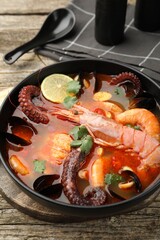 Delicious seafood soup served on wooden table, closeup