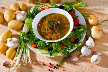 Top view of tasty goulash from chicken hearts with lettuce at plate, fresh vegetables