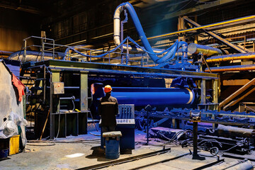 Factory engineer operates pipe painting automatic machine