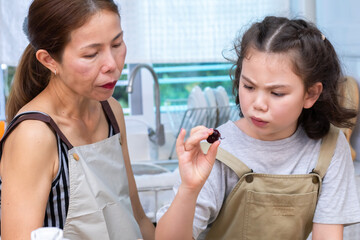 Smiling mother pouring orange juice into a glass for cheerful daughter, capturing family bonding and care, woman and child sharing a happy moment, happiness and warmth in kitchen atmosphere