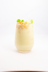 creamy banana smoothie topped with cereal flakes and fresh mint served in clear glass on white background. High quality photo