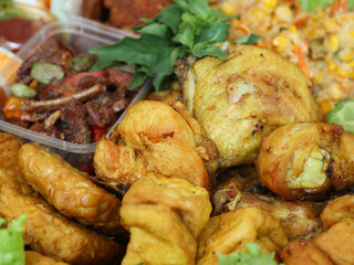 "Crispy, golden-brown fried chicken served as part of a traditional Indonesian tumpeng platter. Placed alongside fragrant yellow rice, fresh vegetables, sambal eggs, and other flavorful side dishes