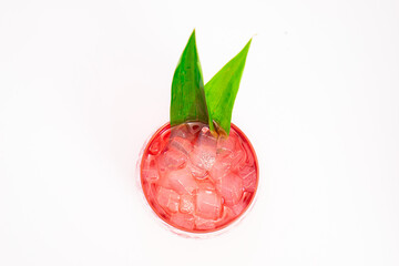red berry cocktail served in clear glass with crushed ice and green tropical leaves isolated on...