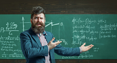 Teacher explains math in class. Professor in classroom on math lesson. University professor writes math formula. Bearded teacher. Professor teaching lesson in classroom. Professor explains math.