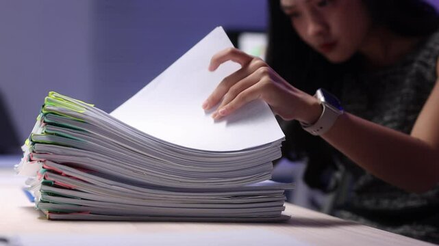 Office worker checking documents at late-night in office, analyzing financial documents.