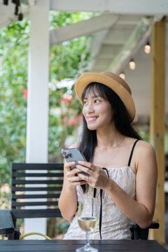Happy Asian Woman Video Calling and Texting on Smartphone While Traveling.