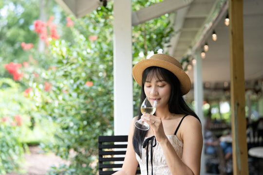 Elegant Asian Woman Savoring White Wine at a Scenic Winery.