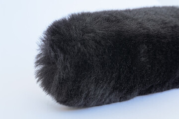 close up of black fluffy faux wool fur car wheel spoke brush, microphone wind screen, wind protector