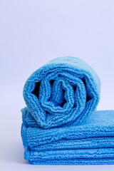 Vertical shot of rolled blue microfiber towel with low pile height on stack of towel isolated on white background