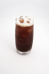 iced coffee or cold brew in tall clear glass with ice cubes and creamy foam served on white background. High quality photo