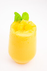 mango or peach smoothie with ice or fruit cubes served in transparent glass and topped with fresh mint leaves on white background. High quality photo