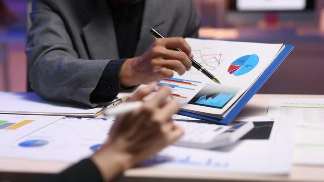 Business people analyzing financial charts and graphs, discussing company growth and planning investment strategies in a collaborative office.