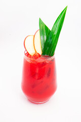 red apple cocktail with ice served in clear glass and garnished with tropical green leaves and apple slices on white background. High quality photo
