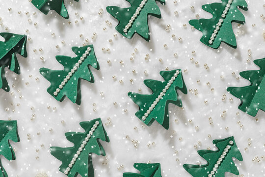 Minimal pattern from Green Christmas trees cut out of paper and snow on white fur, winter holiday background, snowing. Homemade green tree firs decorated pearls. Aesthetic top view, xmas holidays