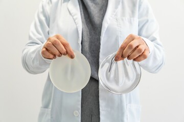 Doctor comparing two silicone implants.