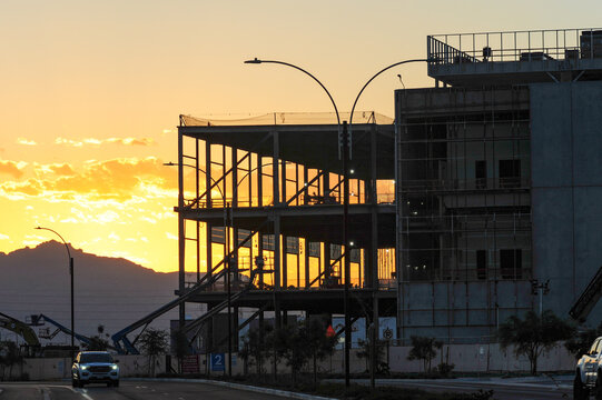 Steel frame and exterior walls of a large-scale data center under construction at sunrise, showing structural progress and utility equipment in a growing tech infrastructure zone