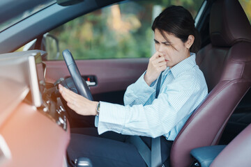Asian woman hold nose because bad smell after turn on air conditioning in car. Woman driving car...