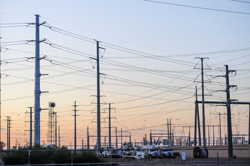 High-voltage transmission lines and utility trucks at an electrical substation, illustrating grid infrastructure and power distribution systems at dawn