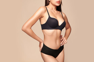 Obraz premium Confident beautiful young asian woman posing in black lingerie on beige background, Perfect body,