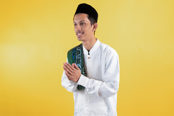 Muslim man wear white shirts with Islamic ornaments and a prayer mat on the shoulder with greeting...