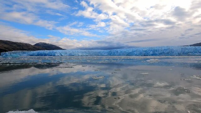 Motoring quickly in a fast boat through brash ice adjacent to the naturally blue Chile PIO XI Glacier and POV of the reflection of the glacier in the clear calm water