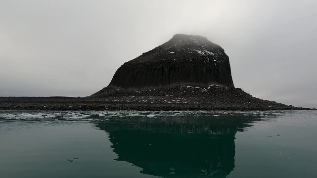Sailing along Edinburgh Hill South Shetland Island Antarctic Peninsula reflection of hill in green sea on overcast day
