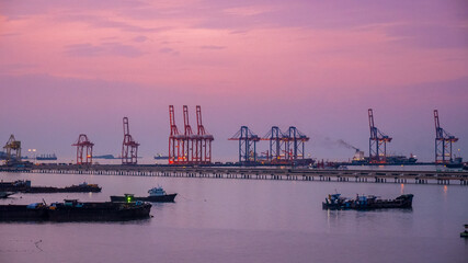 Obraz premium Logistic shipping quay boat in twilight sky night Engineering crane depot at logistic export terminal control. Warehouse freight background container yard loading quayside harbor port Logistics.
