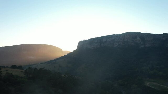 Sunrising over the Lake Elland reserve in South Africa. The sun is slowly revealed over the mountain as the drone climbs.