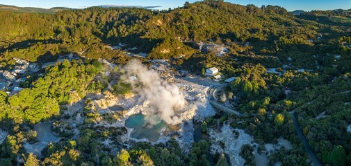 Aerial view of Wai-O-Tapu geothermal area, near Rotorua, New Zealand. Steam rises from hot springs and mud pools. Tourists visit to experience the unique landscape.