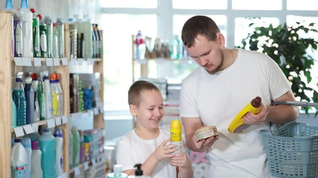 Young man with his son buyers choosing parquet and wood cleaner in household chemicals store