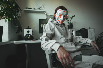 Modern hacker character in street-style clothing and LED mask leans back with confident posture,...
