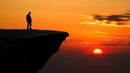 Silhouette at sunset overlooking cliff edge