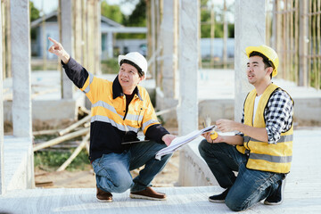 Engineers and contractors discussing blueprints on construction site—teamwork, safety, and...